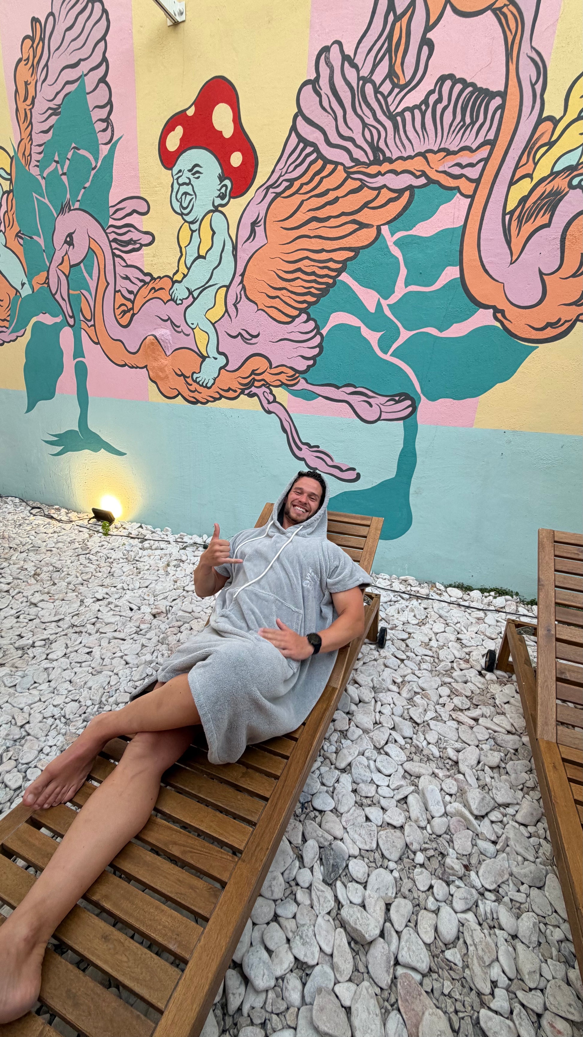 Guy wearing Silver Gray Premium Surf Poncho in outside Sauna area on Summer bed
